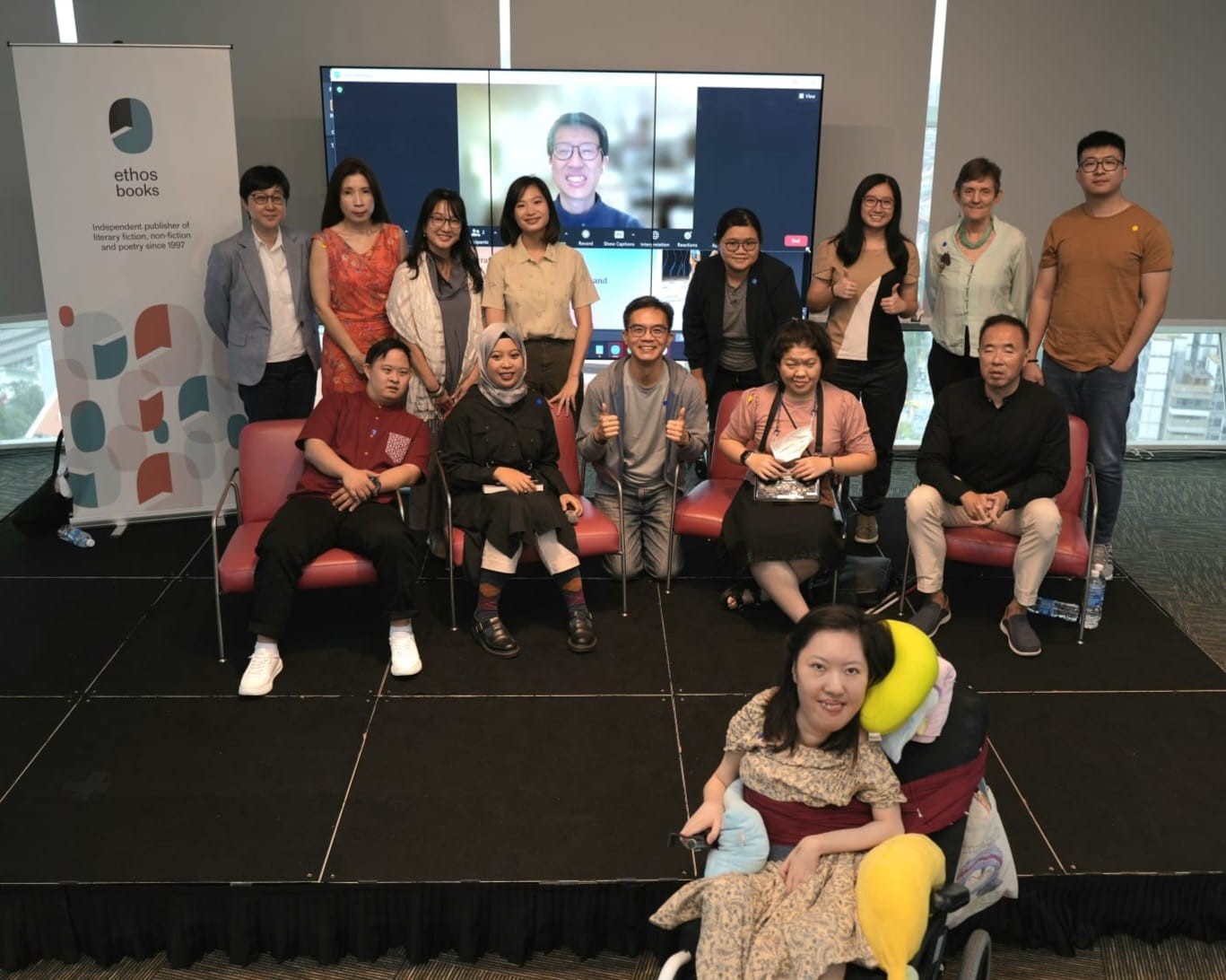 Siew Ling taking a group photo with the editors and other contributors to the book at the launch event. Her friend, Victor, who dialled in for the event, poses from his Zoom screen.