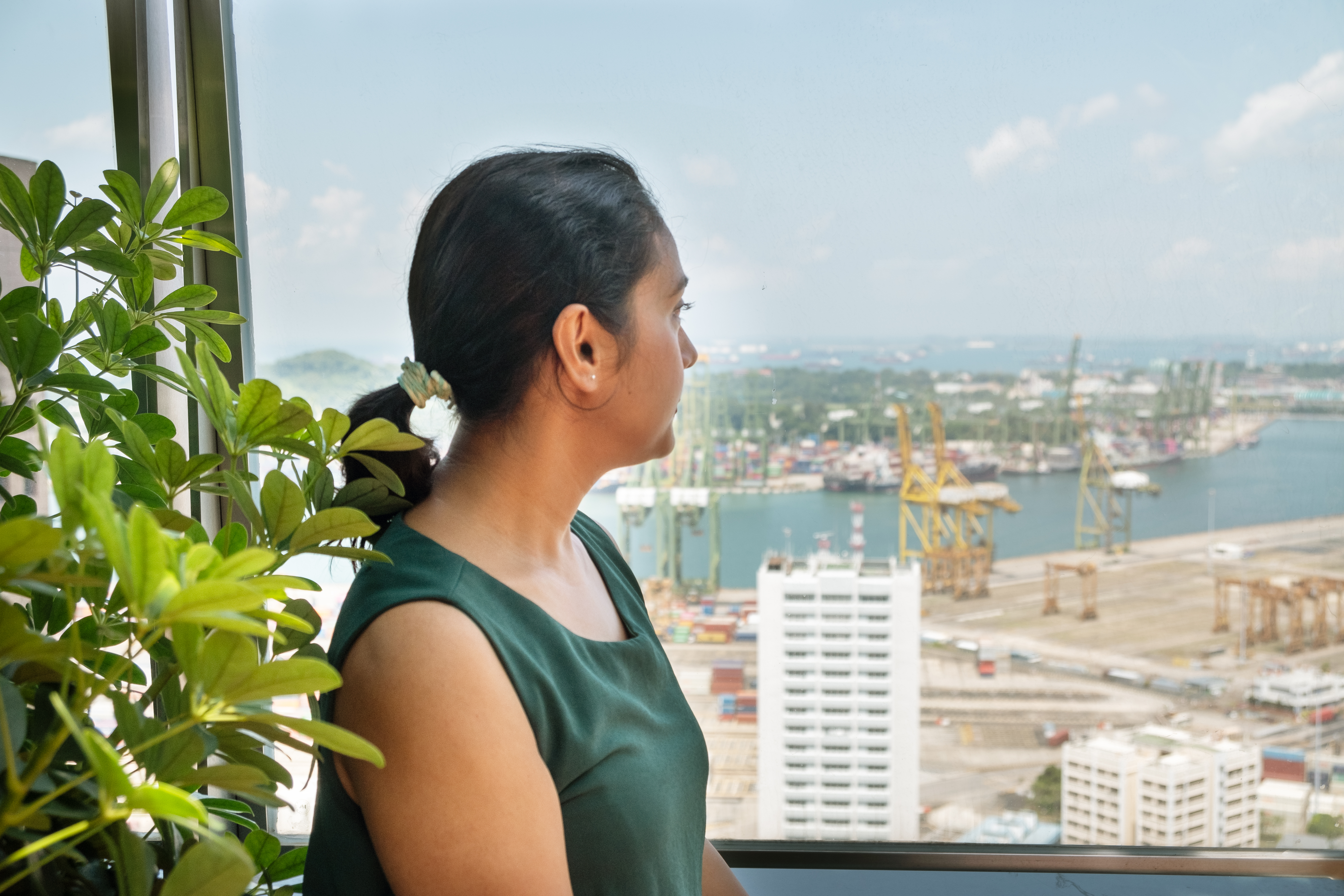 Debanjana contemplatively observes the ocean and distant cargo containers.