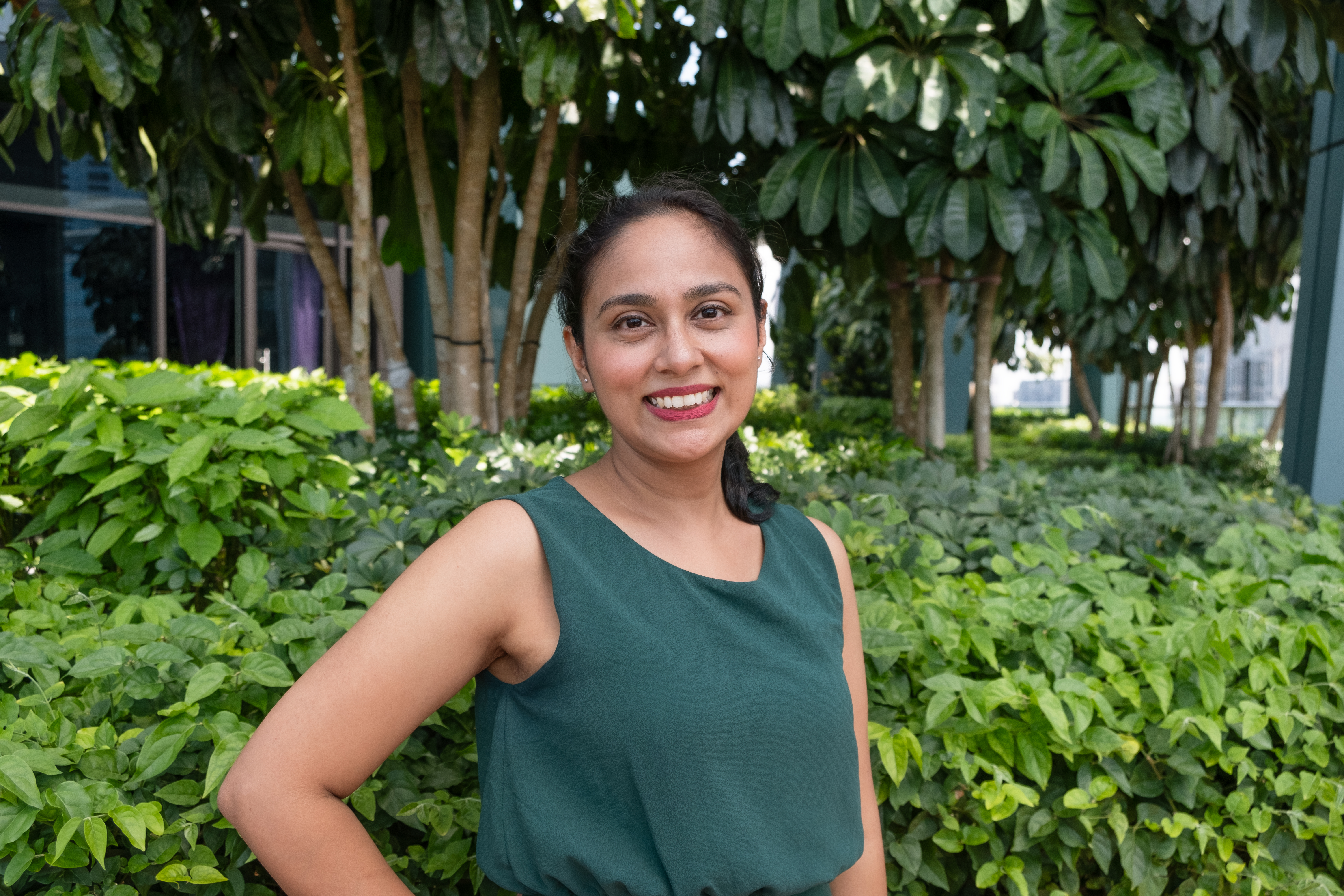 Debanjana posing amidst greenery and smiling widely at the camera.