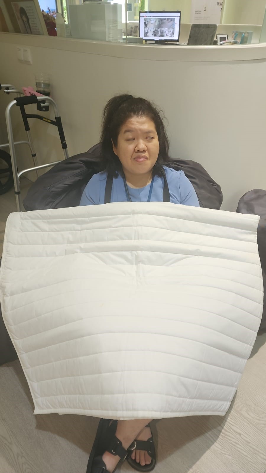 Siew Ling sitting on a chair with the weighted blanket over her.