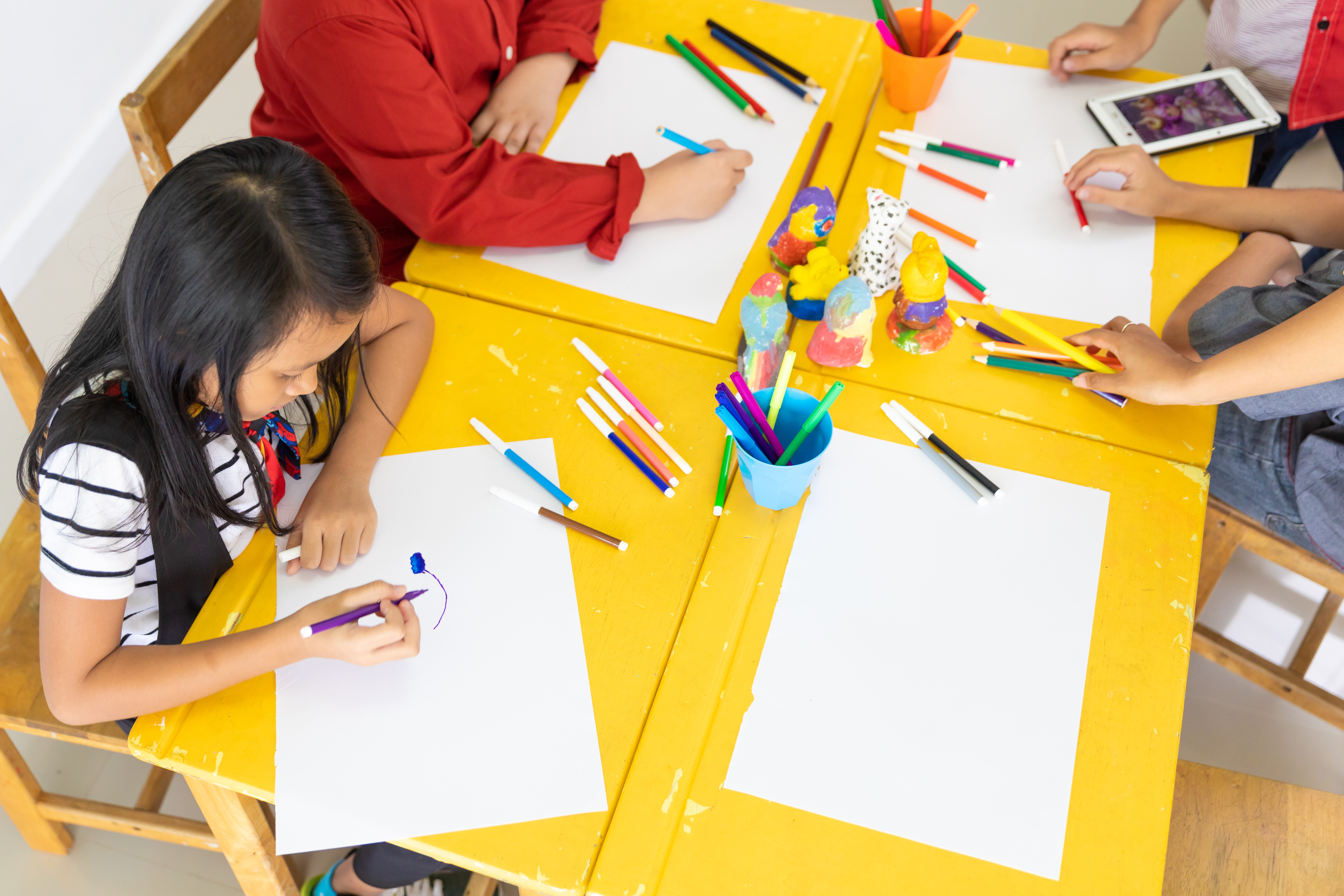 A group of children seated at a table to draw at a student care centre.